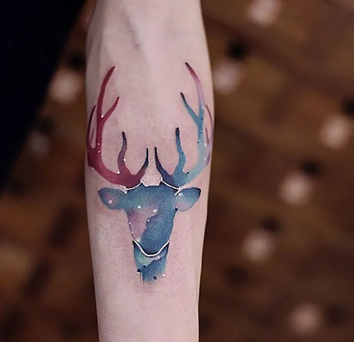 Watercolor tattoo of a colorful deer design on an arm, showcasing Chen Jie's artistic style.
