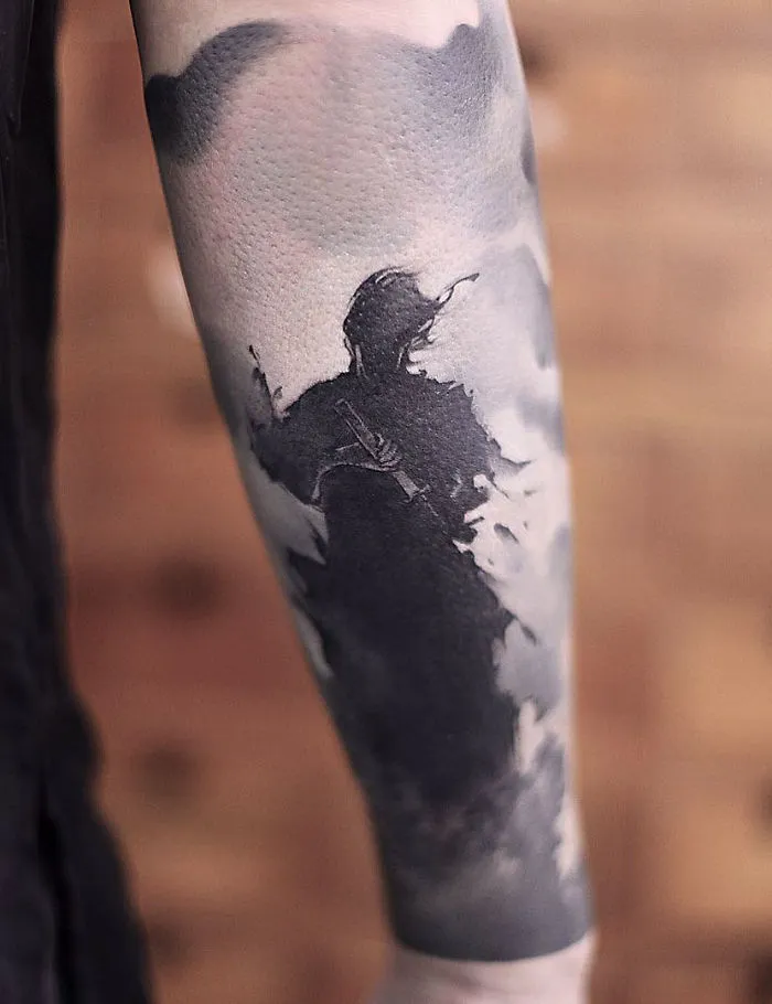 Watercolor tattoo by Chen Jie on forearm, featuring a silhouette design blending into cloud-like patterns.