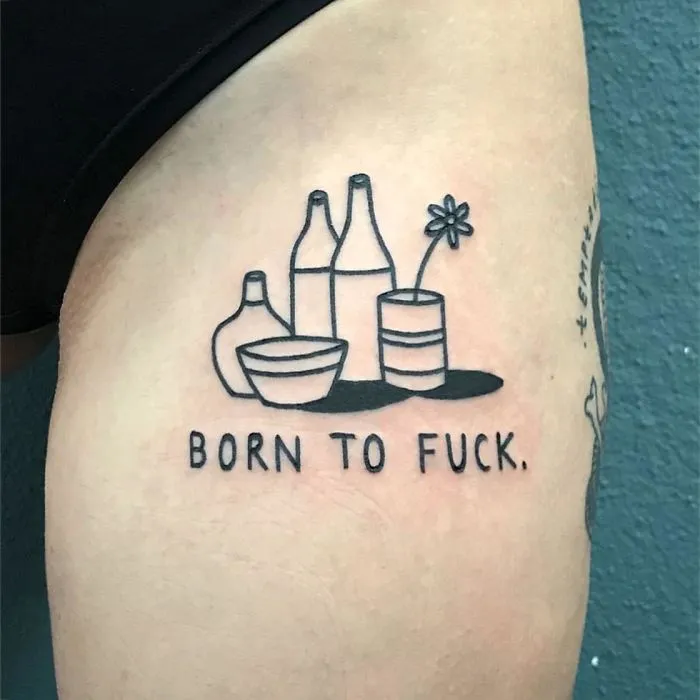 Irreverent tattoo by German artist, featuring bottles and a flower with bold text on the skin.