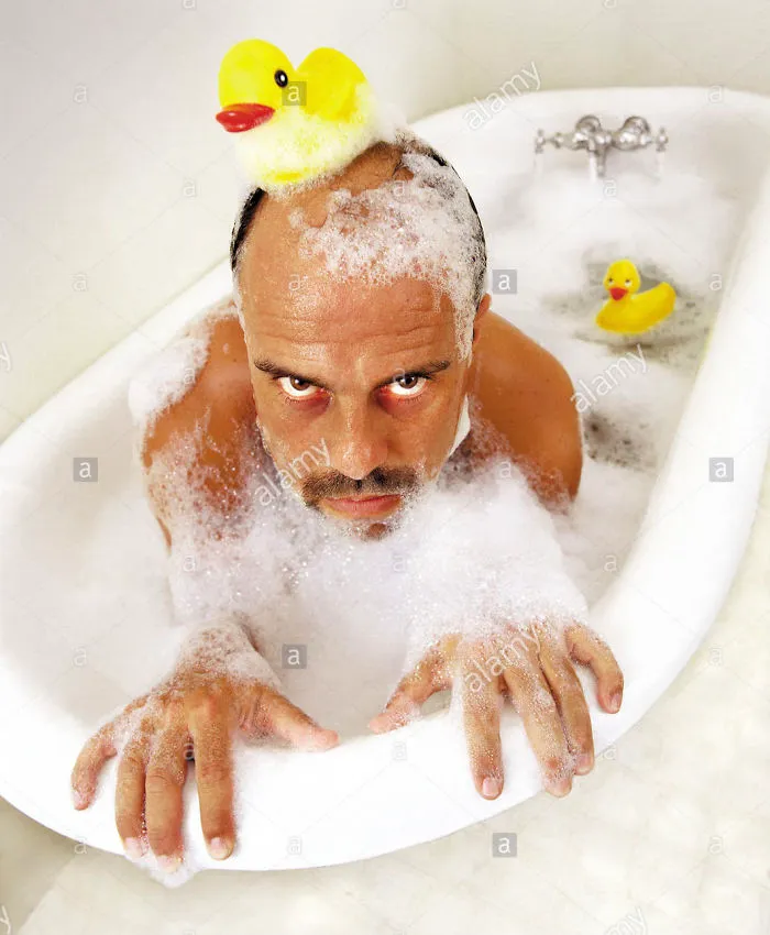 Man in a bubble bathtub with a rubber duck on his head