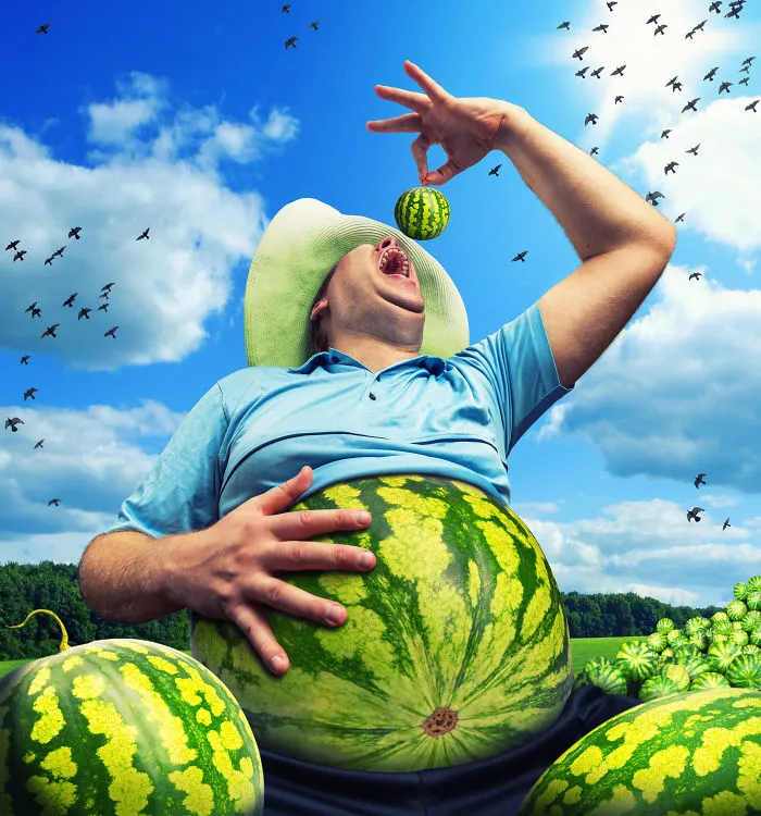 Bizarre farmer with watermelon instead of the abdomen on the field with watermelons in summer