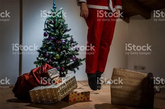 Santa hanged himself near a decorated Christmas tree with presents