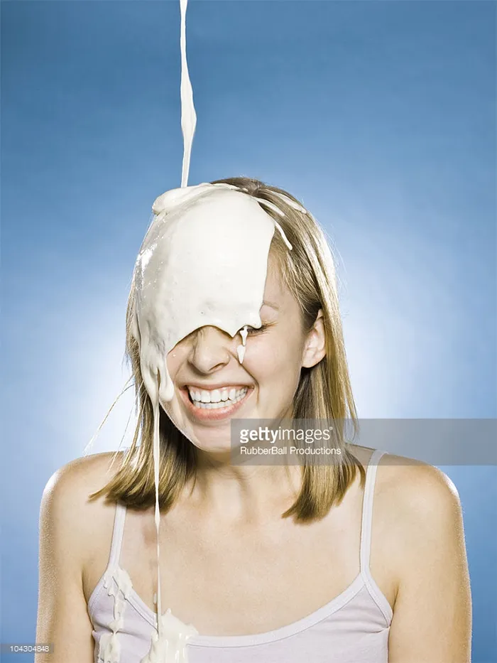 Happy young woman and yoghurt heavily dripping on her head