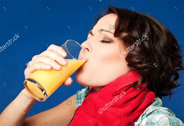 A young woman drinking orange juice in pain while being strangled by the throat