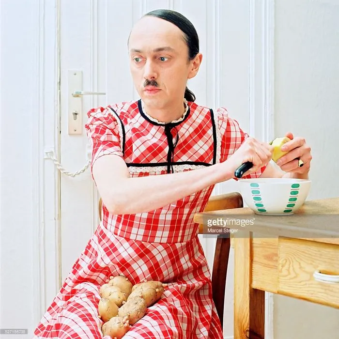 Hitler pelando patatas con un vestido que parece un mantel