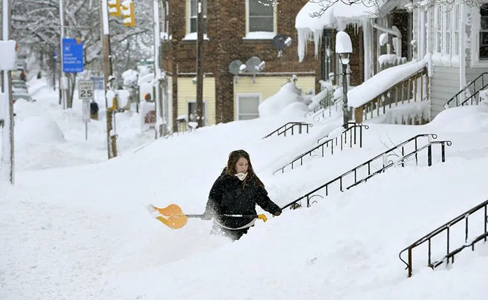 Mujer limpiando su entrada tras una nevada récord