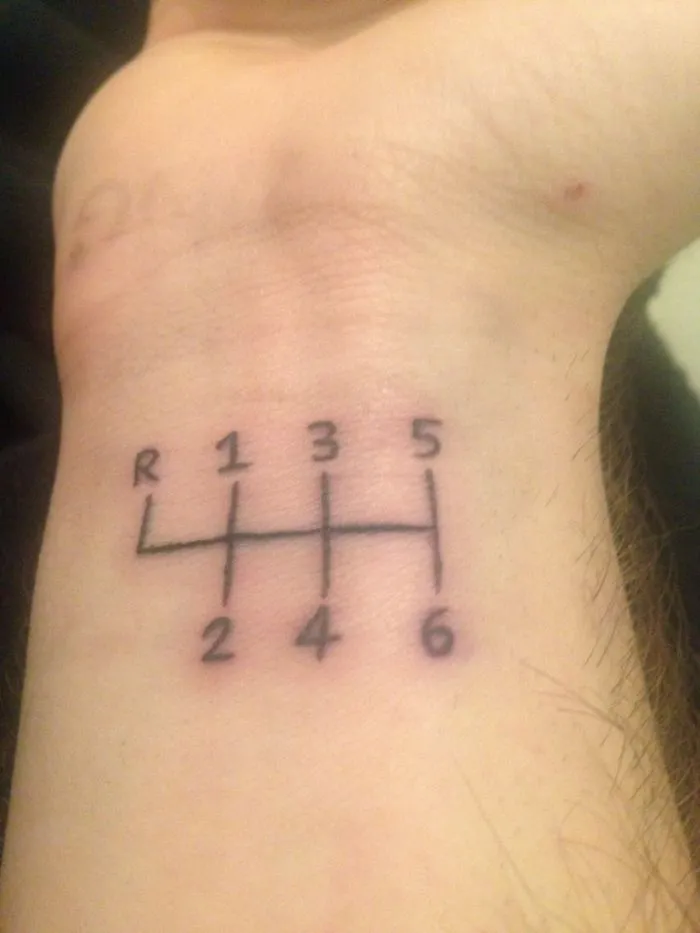 Tattoo of a car's gear shift pattern symbolizing a personal story on a person's forearm.