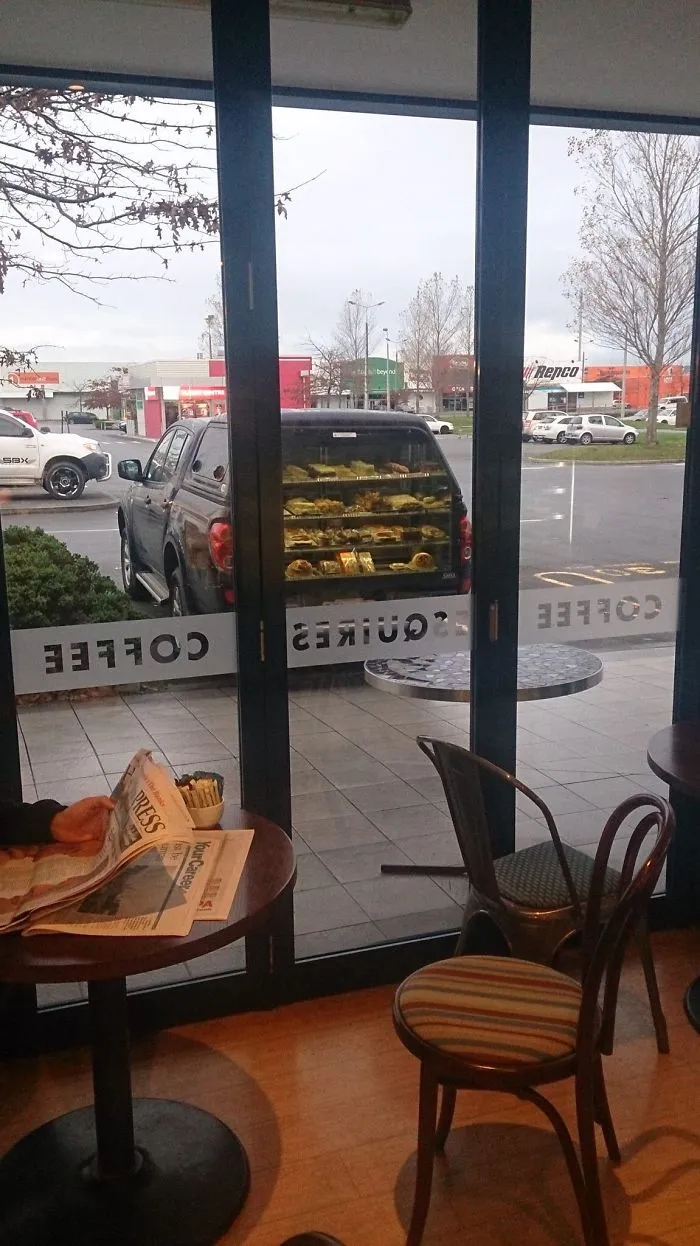 El reflejo del interior de la cafetería hace que parezca que el coche de fuera vende bollería en su maletero