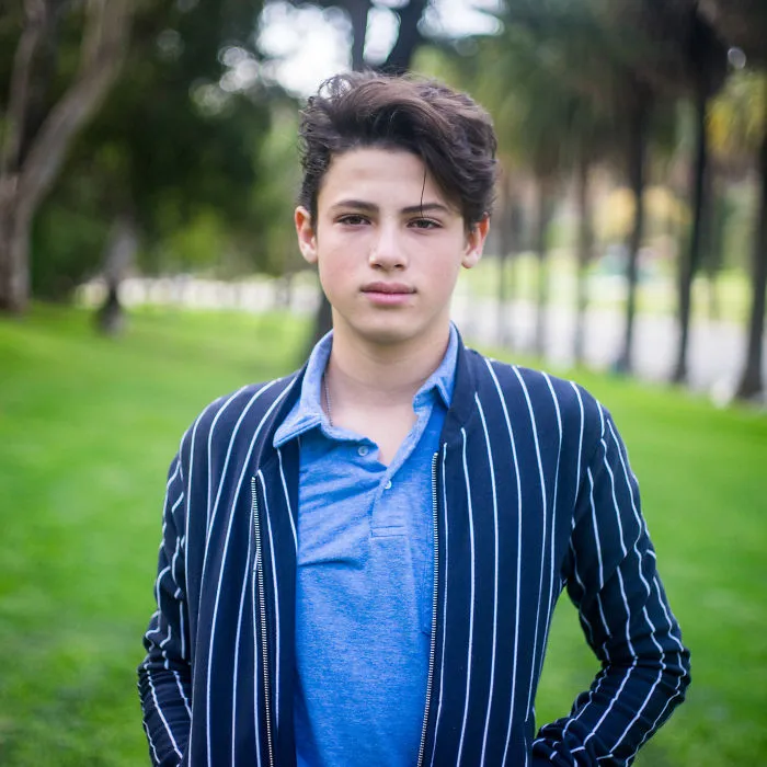 Teenager standing outdoors in a park, representing interviews with people on their birthdays in a casual setting.