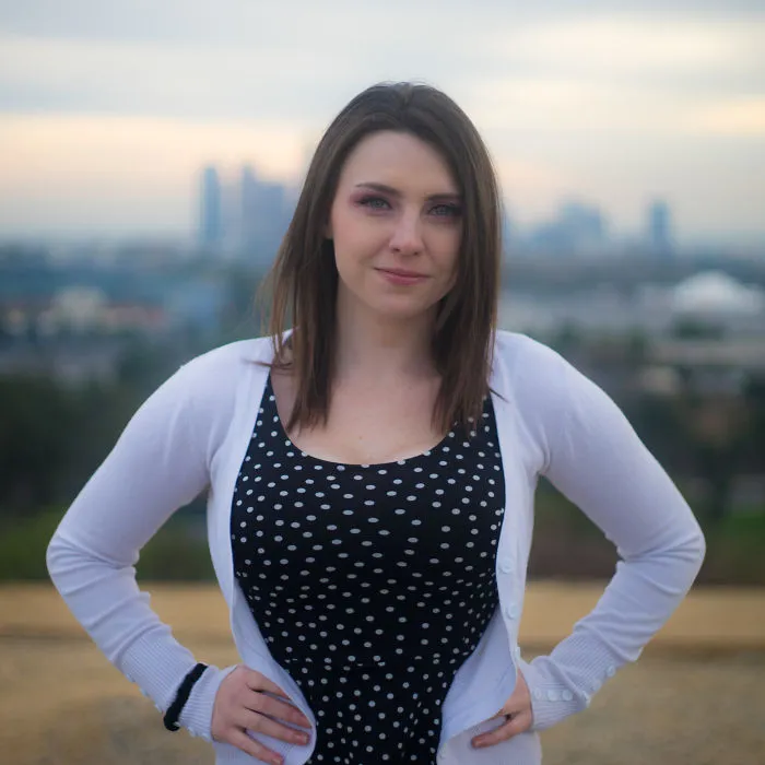 Woman standing outdoors with hands on hips, smiling confidently during a birthday interview session.