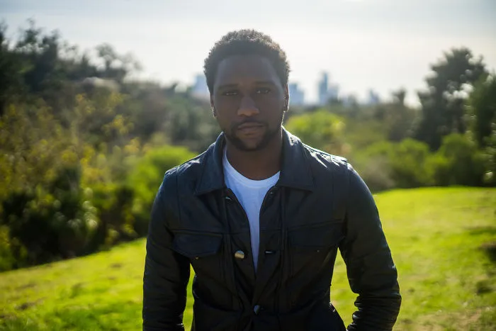 Man outdoors in a black leather jacket, posing in a park setting, representing interviews on their birthdays.