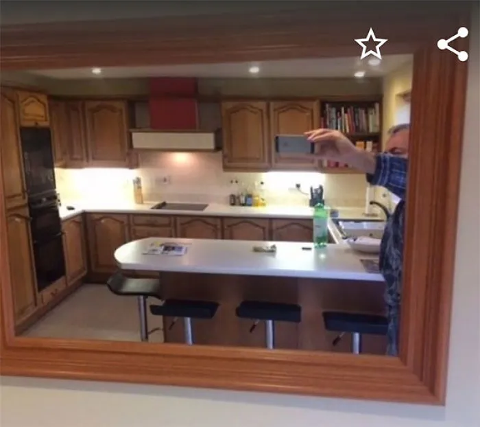Person taking a mirror selfie in a kitchen, capturing the room's reflection, highlighting the art of selling mirrors.