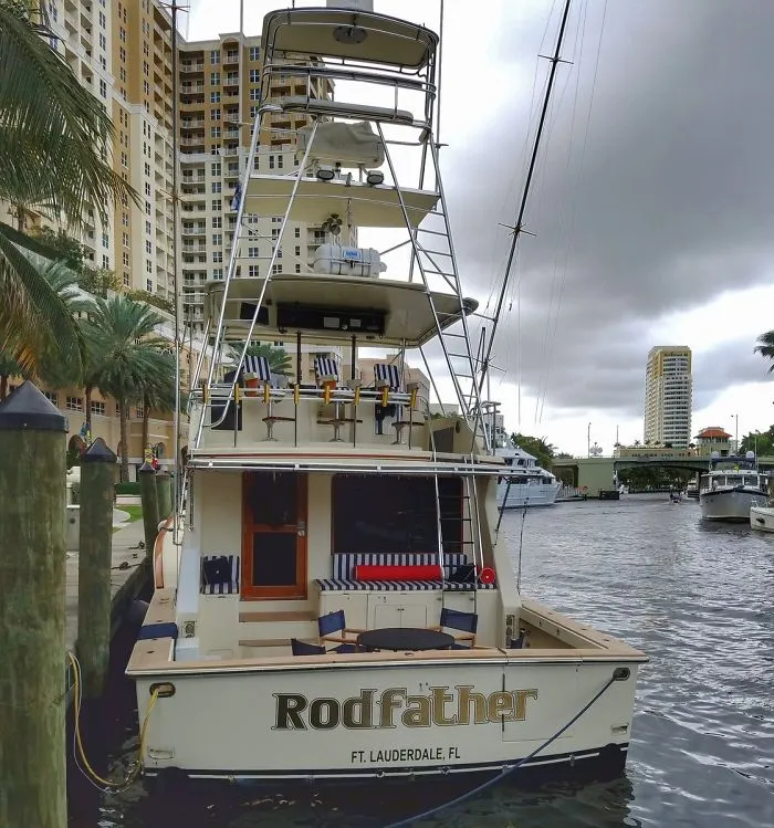 Clever named tall fishing boat docked near houses 