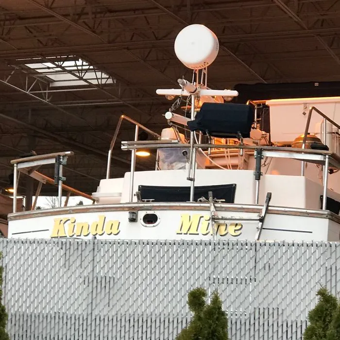 Funny named white boat behind the fence 