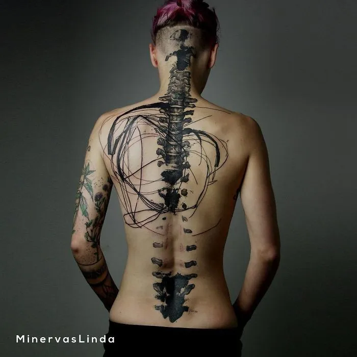 Back view of a person with an intricate spine tattoo design featuring abstract patterns.