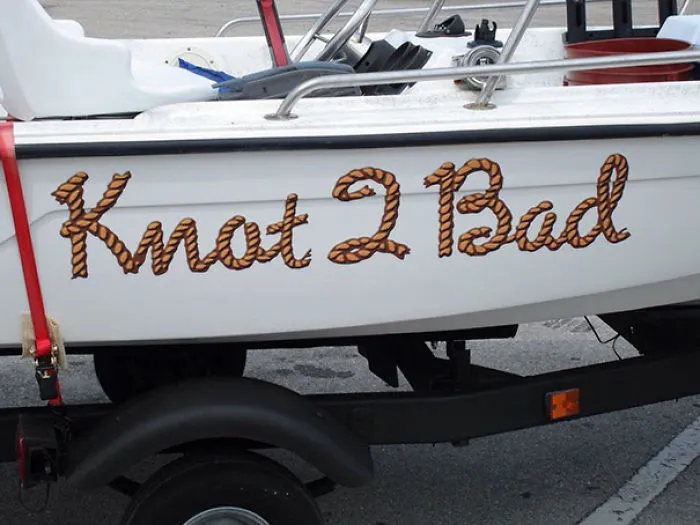 Funny named white boat being pulled in a trailer