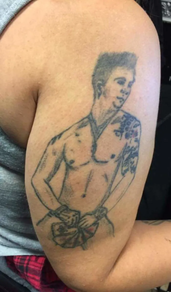 Tattoo fails: uneven sketch of a man on upper arm, with visible tattoo details and shading.