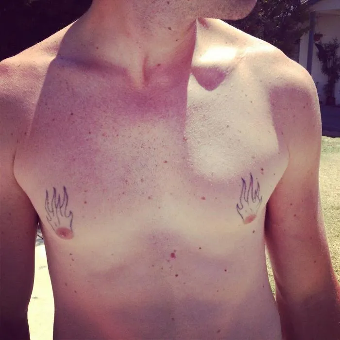 Man with a tattoo fail featuring small flame designs above his nipples, showcasing a humorous and cringeworthy tattoo choice.