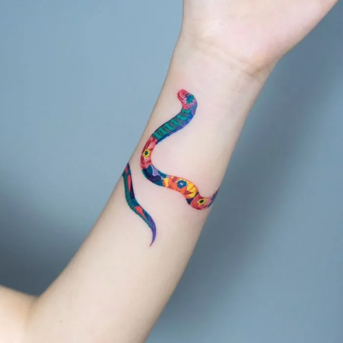 Snake tattoo art by Korean artist on forearm, featuring vibrant colors and intricate patterns.
