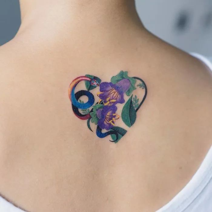Colorful snake tattoo on a person's shoulder, designed by a Korean artist, incorporating flowers and leaves.