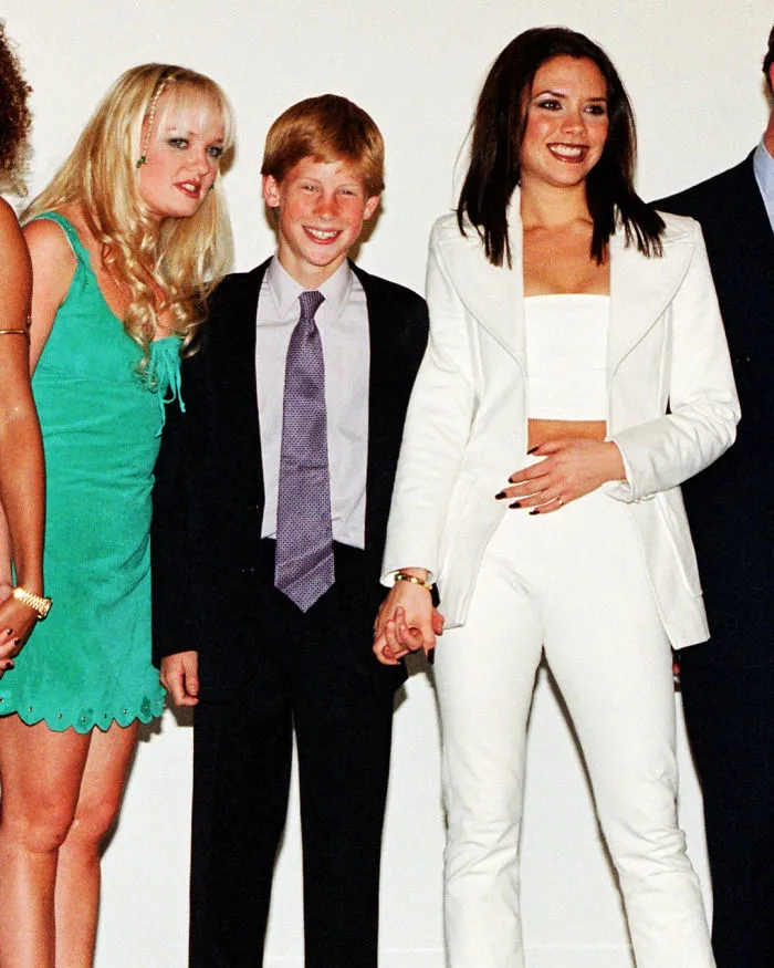 El príncipe Harry dándole la mano a Victoria Beckham mientras posa con su padre junto a las Spice Girls, 1997