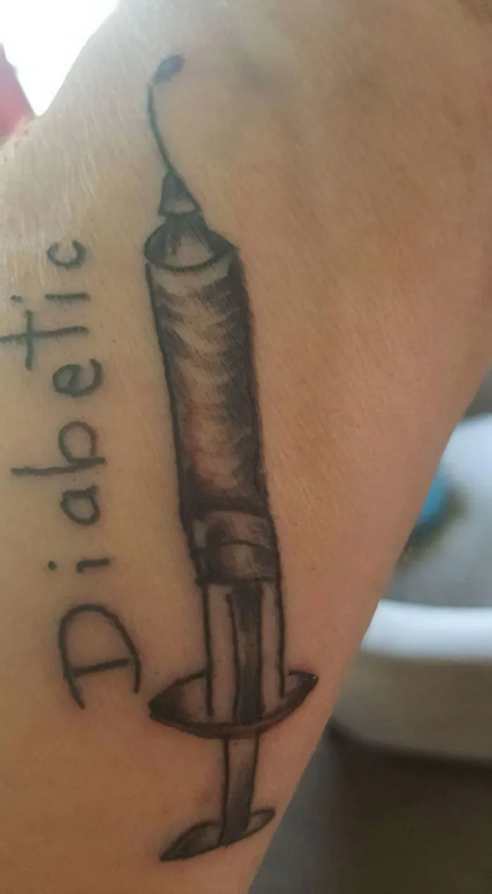 Tattoo fail of a syringe with the word "Diabetic" on a forearm, showcasing a humorous design error.