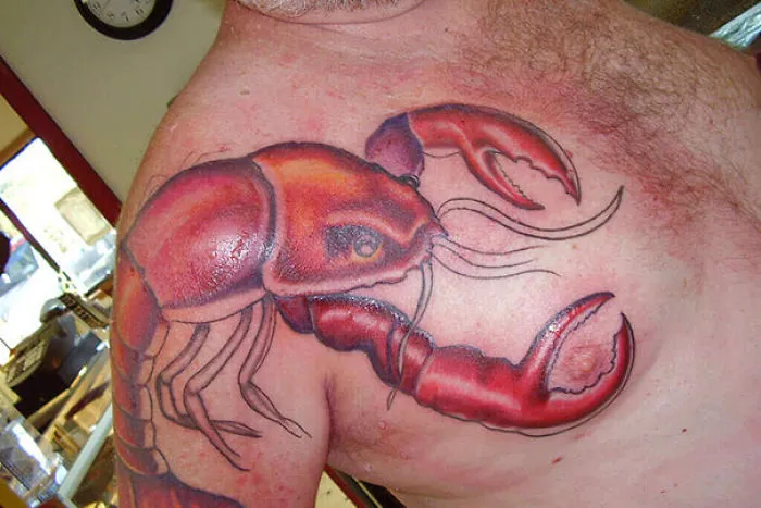 Bad tattoo fail featuring a large lobster design on a man's chest.