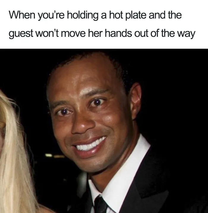 Restaurant meme with a man smiling awkwardly, capturing the humor of holding a hot plate while a guest's hands are in the way.