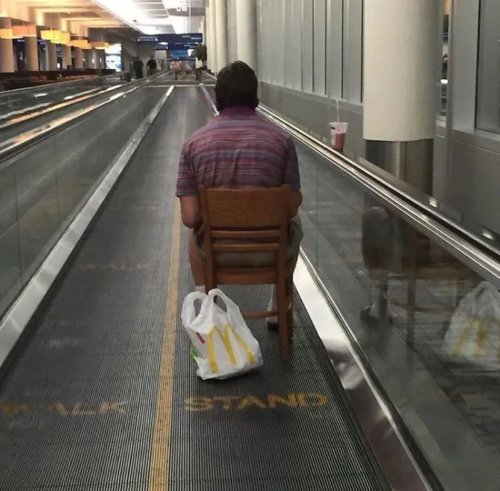 En el pasillo móvil del aeropuerto, sentado en su silla, comiendo hamburguesa y cazando pokemon