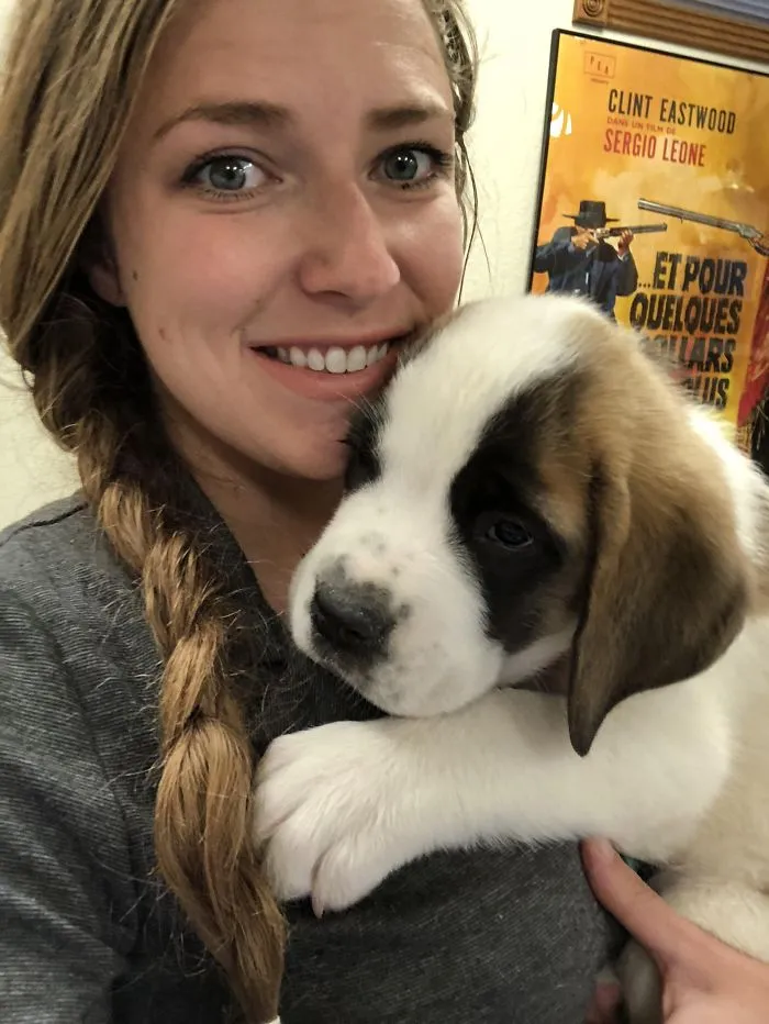 A cute puppy nestled in the arms of a smiling person, showcasing adorable charm.