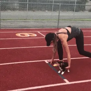 Woman and cute puppy at the starting line on a track, ready to run.