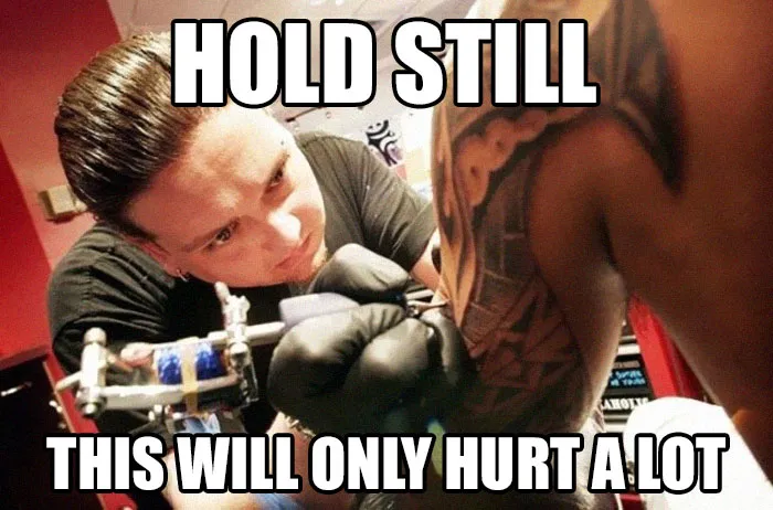 Tattoo artist working on a client's arm with funny meme text about pain.