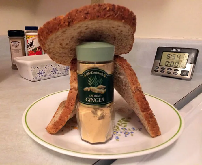 Funniest dads create a gingerbread house using a ginger bottle and bread slices on a kitchen counter.