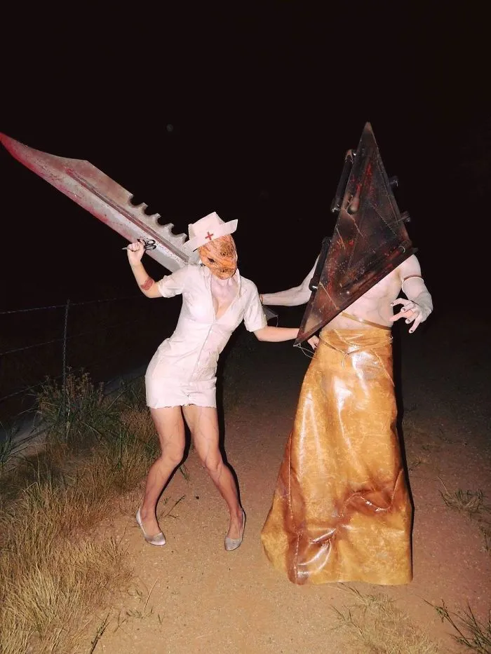 Couple in creative horror costumes wielding large weapons, showcasing standout Halloween attire.