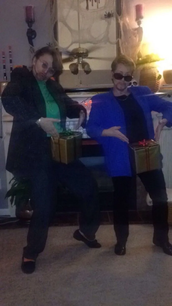 Couple in coordinated Halloween costumes, posing with wrapped boxes, embodying a humorous theme.