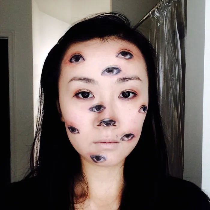 Woman with realistic extra eyes painted on her face, a spooky Halloween costume idea