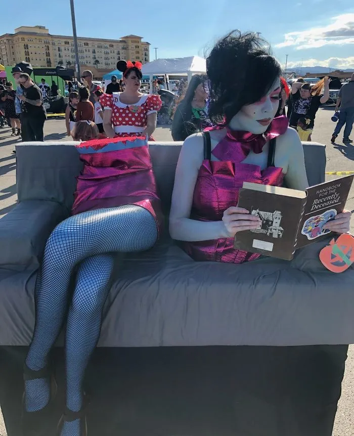 A woman in a clever Halloween costume idea depicting a sawed-in-half ghost reading a book on a couch outdoors.