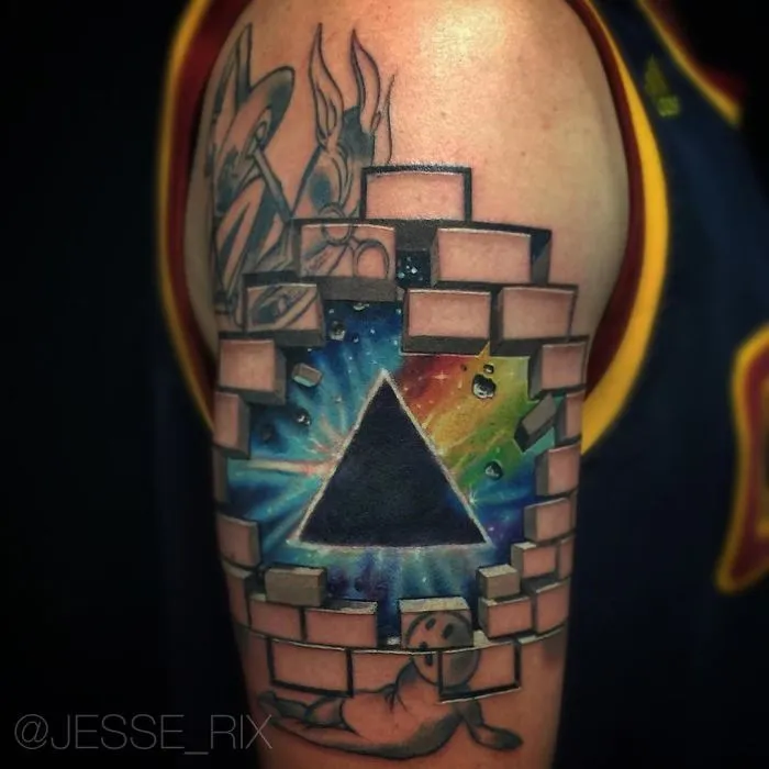 3D tattoo of a pyramid breaking through bricks on an arm, featuring vibrant colors and detailed design.
