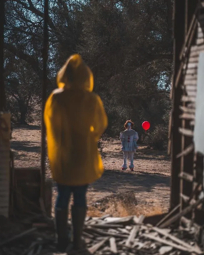Couples Halloween costume ideas inspired by IT, with one person in a yellow raincoat facing Pennywise the Clown.
