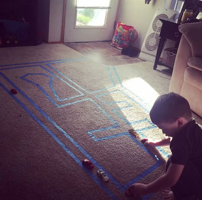 Pon cinta de pintor en la alfombra para que tu hijo juegue con cochecitos