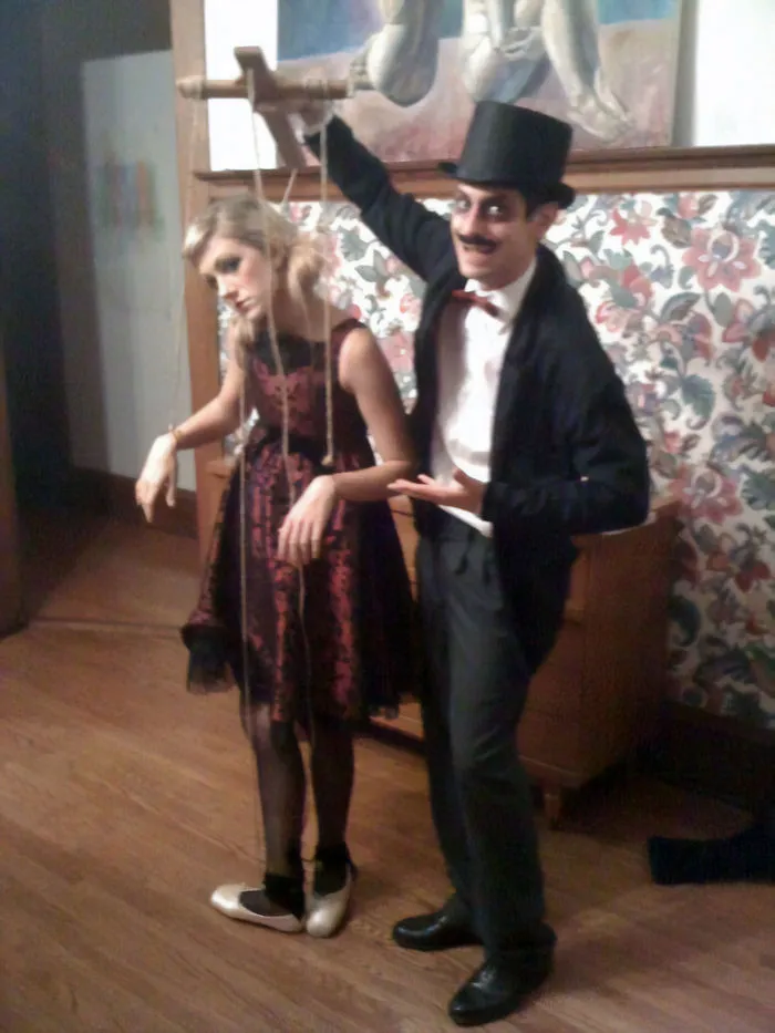 A man in a top hat controlling a woman like a marionette, showcasing creative couples Halloween costume ideas.