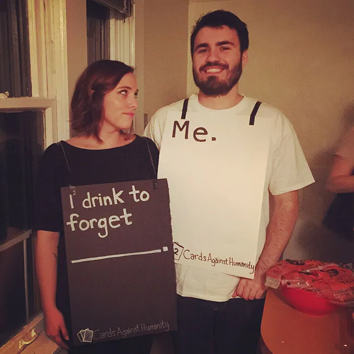 A couple wearing Cards Against Humanity cards as a funny couples Halloween costume idea.