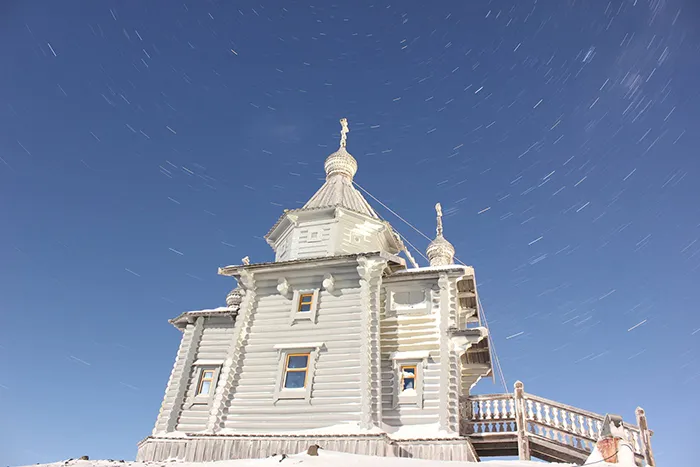 Wooden structure covered in snow under a starry sky, illustrating unbelievable facts about Antarctica's unique environment.
