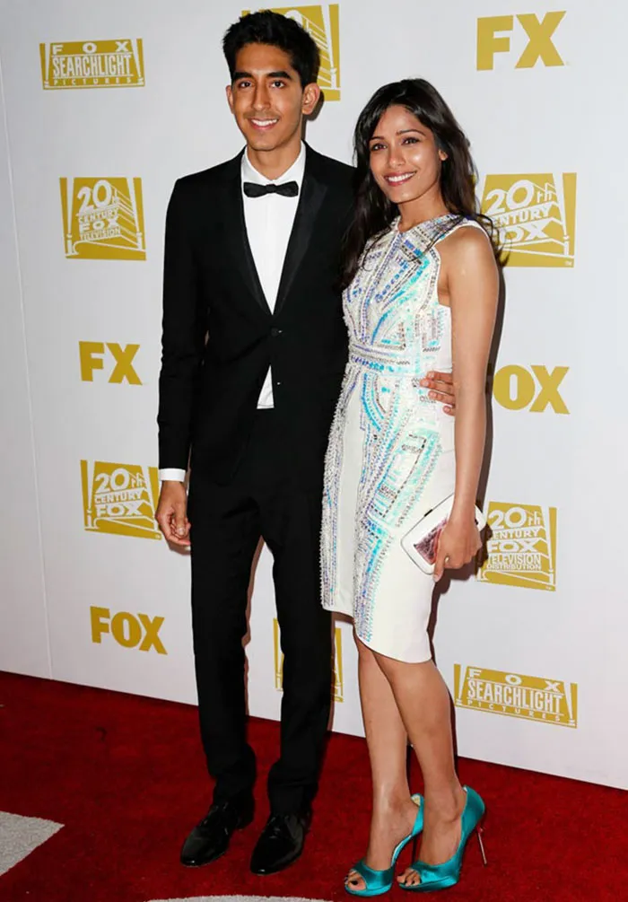 Couple on the red carpet at a film event, dressed elegantly, representing celebrities who fell in love while acting together.
