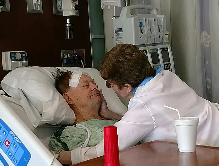 Woman looking at the man who is laying in a hospital bed 