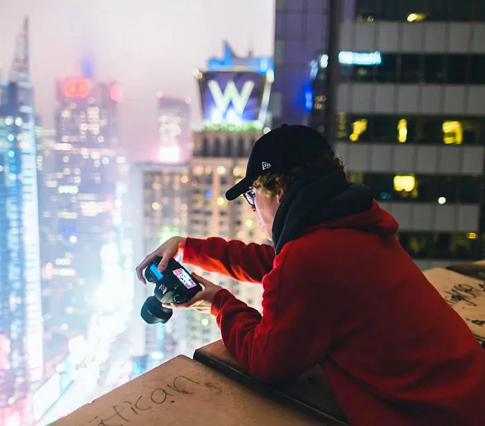 Man taking a picture of something from a tall building 