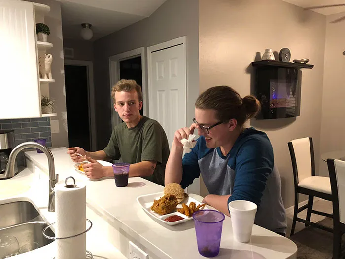 Brother and sister eating on a bar table 