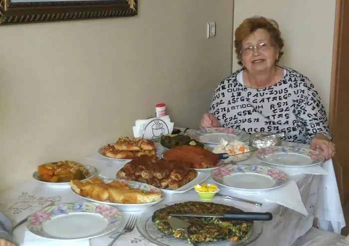 Woman sitting next to table full of food 