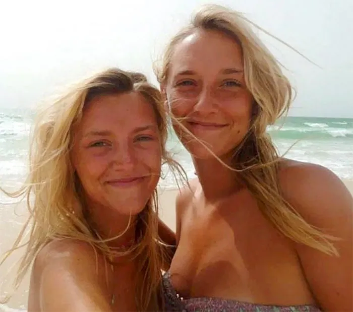 Two best friends posing for a selfie in a beach 