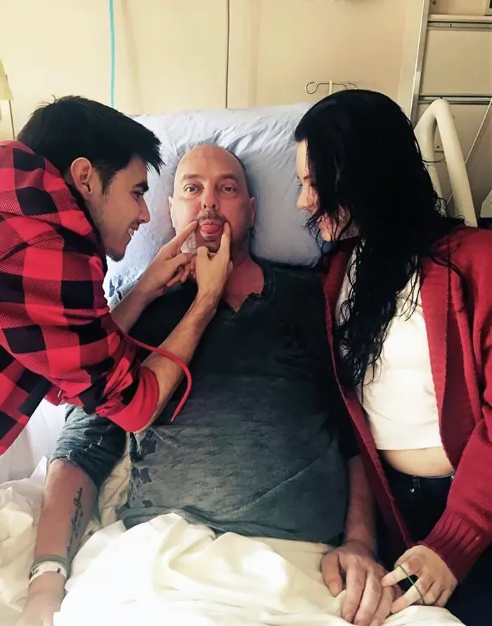 Man laying in hospital bed with his happy children 